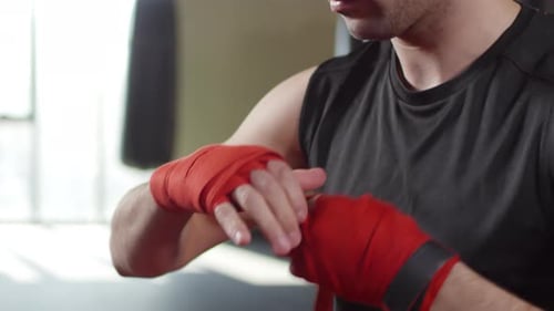 Male Boxer Wrapping Hands in Gym