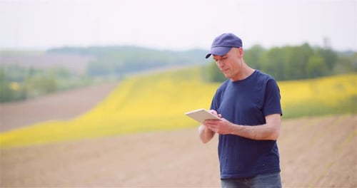 Agriculture Technology Concept - Farmer Examining Agriculture Field Working on Digital Tablet.