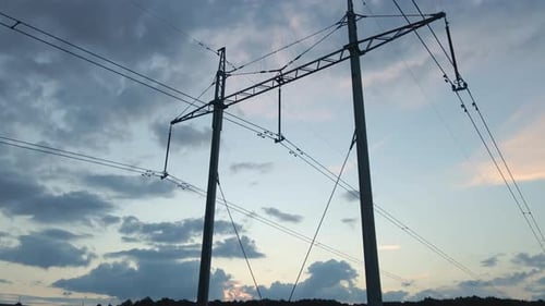 Dark Silhouette of High Voltage Tower with Electric Power Lines at Sunset