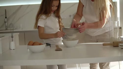 Girl and Woman Baking Together in Sunny Kitchen
