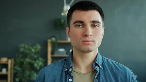 Zeitlupe eines gutaussehenden Mannes mit ernstem Gesicht, der allein in der Wohnung steht