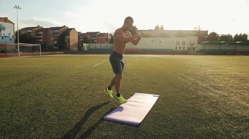 Muscular Man Training in the City Stadium and Doing Jumps and Squats. Healthy Lifestyle. Close-up