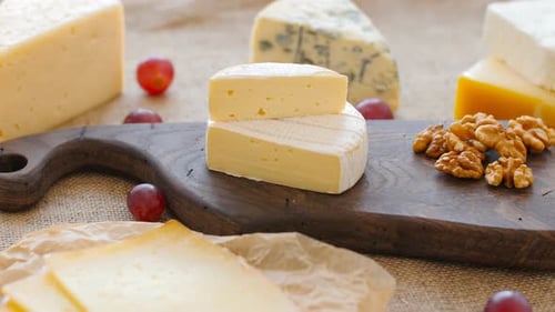 Various Cheeses on Wooden Cutting Board with Grapes