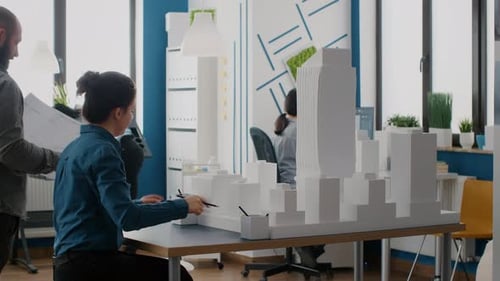 People Working Together to Design Blueprints Plan with Building Model and Maquette