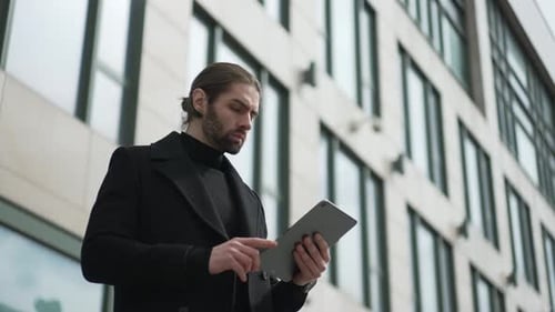 Businessman Using Tablet PC in Front of Offices Building