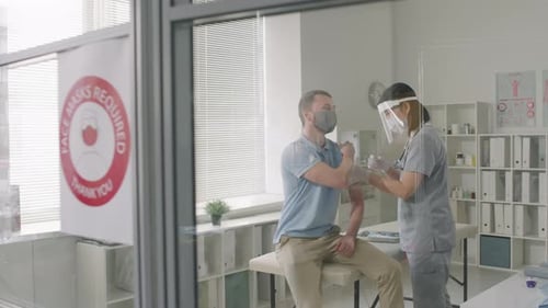 Man Receives Vaccine from Healthcare Worker in Clinic