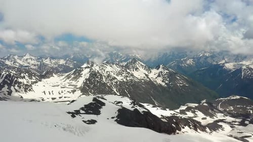 Air Flight Through Mountain Clouds over Beautiful Snow-Capped Peaks of Mountains and Glaciers
