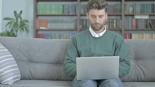 Young Adult Working on Laptop on Sofa