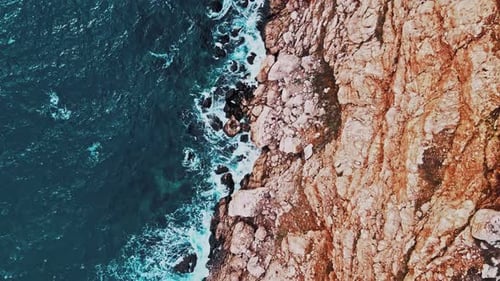 Breathtaking Top Aerial Slow Motion View of Azure Ocean and Waves Crashing at Rocky Cliff