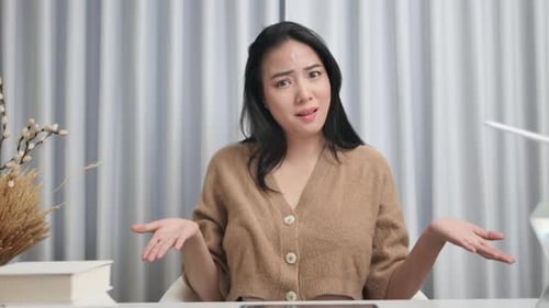 Confused Woman Shrugs at Desk Indoors