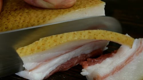 Chef Hand Cuts Large Delicious Raw Pork Lard with Skin in Domestic Kitchen with Sharp Kitchen Knife