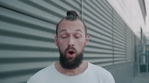 Bearded Man Makes Funny Faces Against Metal Wall