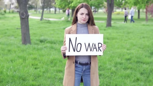 Eine Frau hält ein Banner mit dem Text „Nein zum Krieg“ in der Hand.