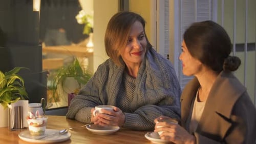 Beste Freunde teilen Kindererinnerungen im Café, lachen und trinken heißen Kaffee