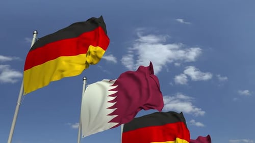 Waving Flags of Qatar and Germany Against Blue Sky