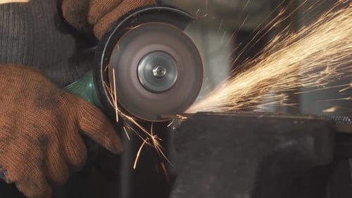 Close-up Side View of Male Hands Cutting Metal with Grinding Machine. Unrecognizable Man in Working