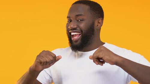 Enthusiastic Man Gesturing Positively on Yellow Background