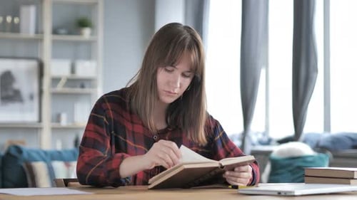 Woman Reading a Book at a Desk Indoors