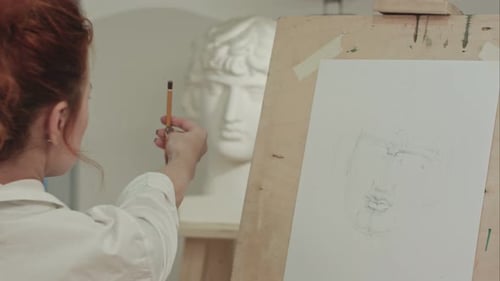 Concentrated Woman Artist Painting Plaster Bust in Art Studio