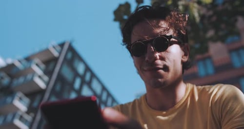 Man smiles while using phone on park bench