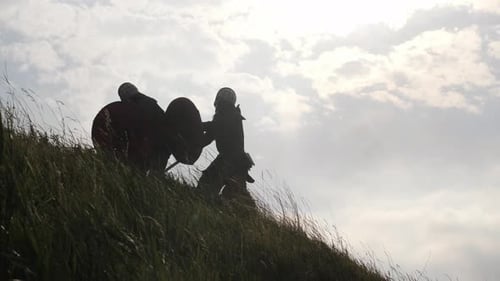 Silhouetted Warriors Fighting with Swords and Shields on Hill