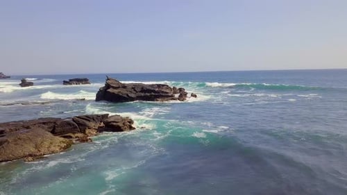 Filmaufnahme eines wunderschönen Küstenstrandes mit Wellen, die auf den Felsen krachen