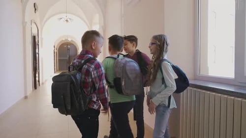 Students Walking Down Bright School Hallway with Backpacks