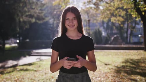 An Attractive Young Lady Using a Phone in Town, Medium Shot