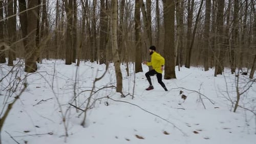 Athlete Running on Snow Among Trees in Winter Forest