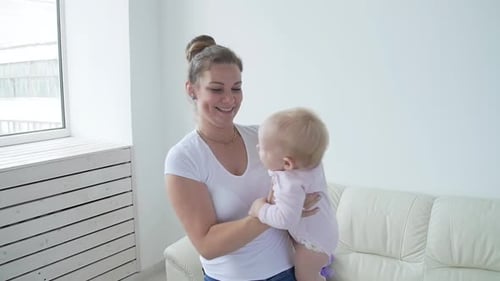 Mother Lifts Blond Baby in Sunny Home