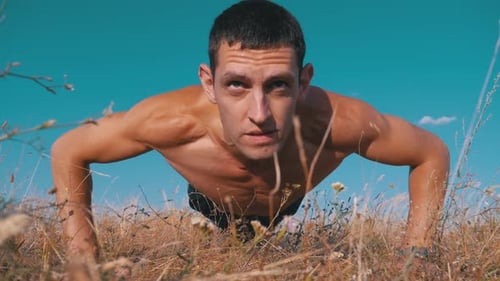 Man Doing Push Ups in Grassy Field