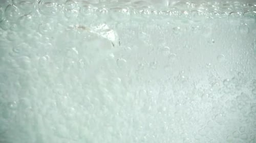 Kohlensäurehaltiges Wasser in das Glas gießen.