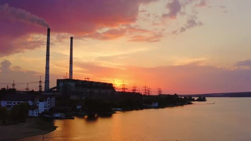 Fábrica dañina contra el cielo rosado al atardecer.