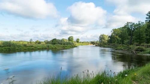 Wolken spiegeln sich im glatten Wasser eines Flusses