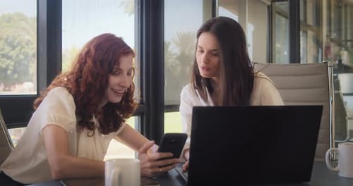Two Women Working Together on Laptop and Phone