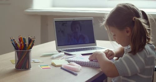 Side View of Teenager Preschool Girl Busy in Writing or Learning Drawing By Looking To Laptop Screen