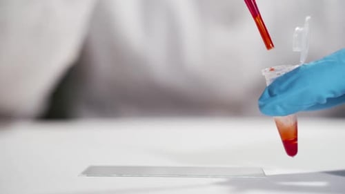 Scientist Drops Liquid onto Glass Slide for Experiment