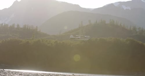 Cessna volant avec des montagnes enneigées et des arbres au loin pendant la journée en Alaska - Aerial Si