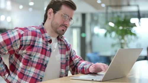 Young Adult With Back Pain Using Laptop