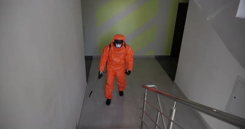 Worker in Protective Suit Walks Down Hallway