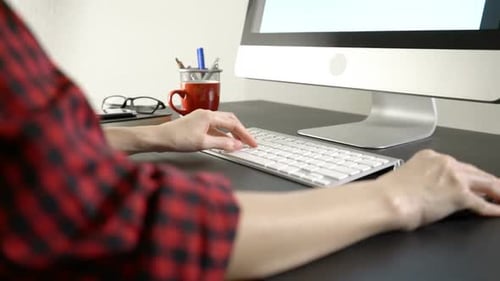 Person Typing on Keyboard at Computer Desk
