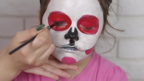 Kid draws face for Halloween.