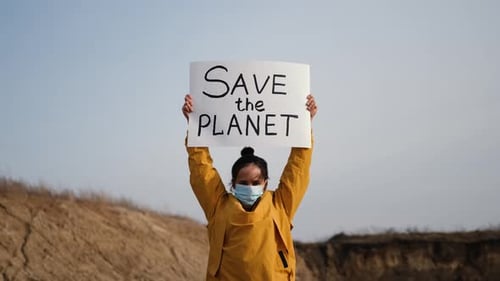 Woman Holds Save Planet Sign in Rural Location