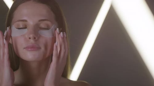 Young Woman Applying Eye Patches on Face