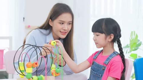 Woman Helping Young Girl Play with Bead Maze