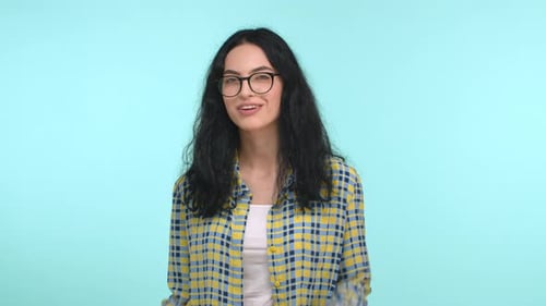 Freches brünettes Mädchen mit Brille zeigt mit dem Finger in die Kamera, zwinkert und lächelt frech und wählt dich aus oder