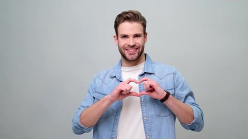 Smiling Man Makes Heart Shape with Hands