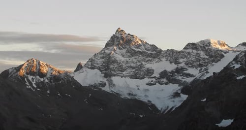 Snowy mountain peak with a beautiful glacier in amazing sunset light. Panorama landscape view of a h