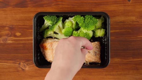 Sprinkling Seeds onto Salmon and Broccoli Meal Prep