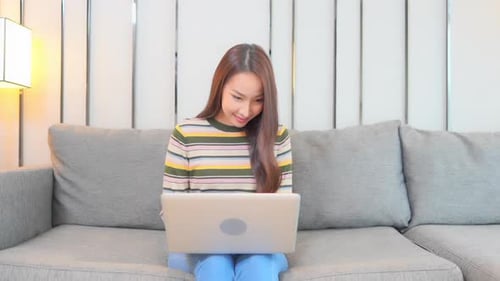 Excited Woman Using Laptop on Sofa